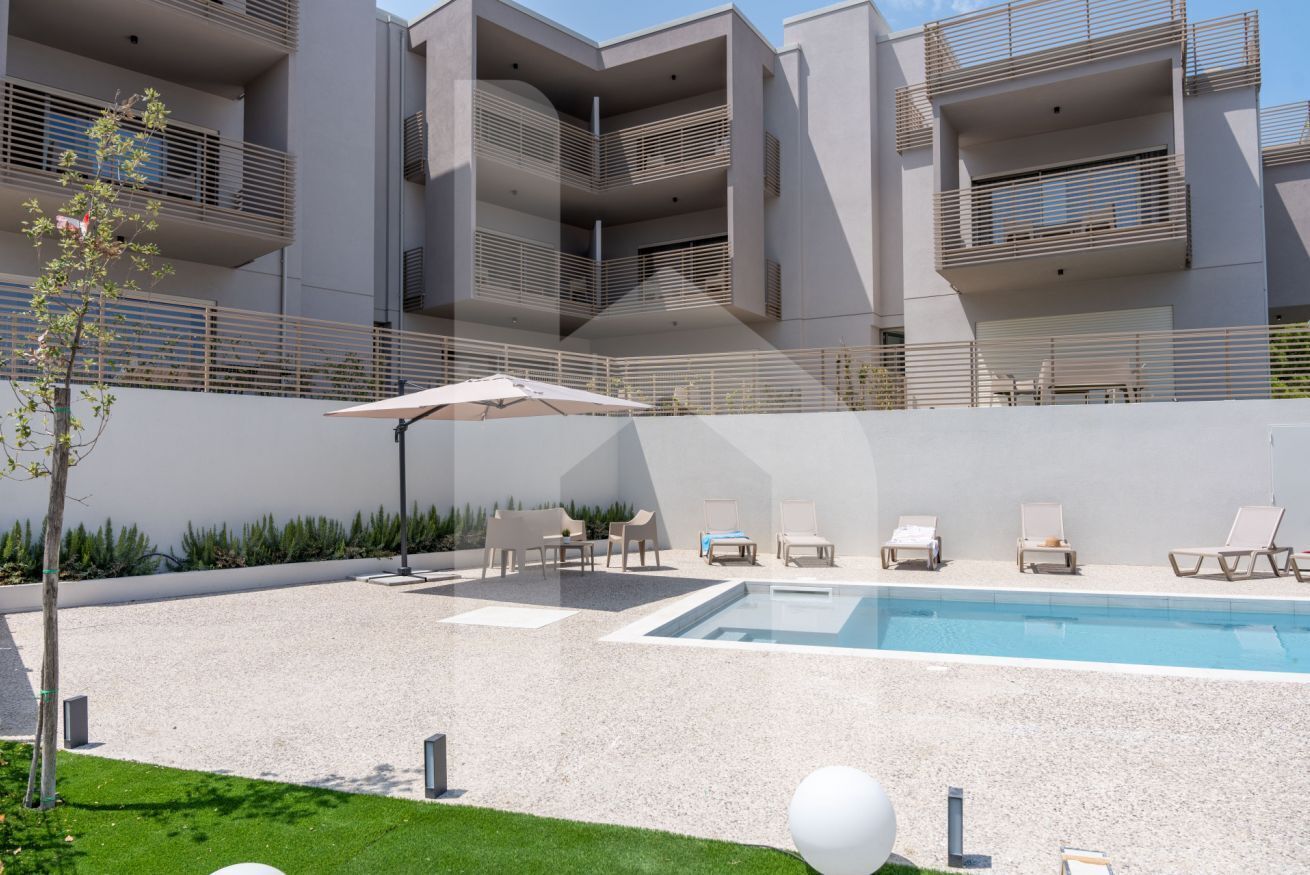 A modern building with a swimming pool, outdoor seating, and a well-maintained garden.
