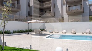 Een modern gebouw met een zwembad, terras en een verzorgde tuin.
