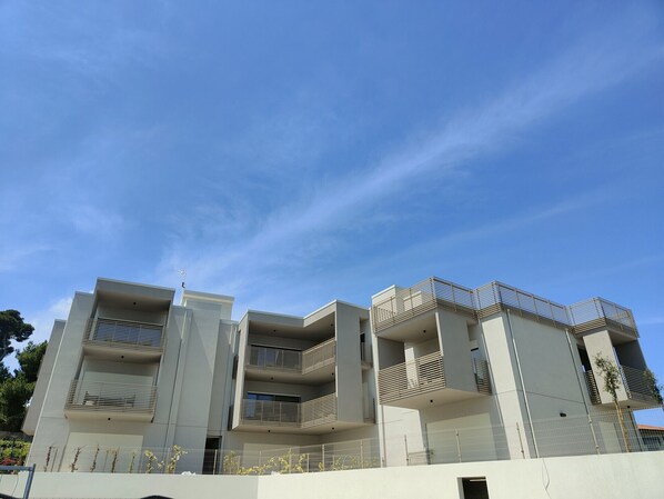 A modern multi-story building with balconies and a clear sky.