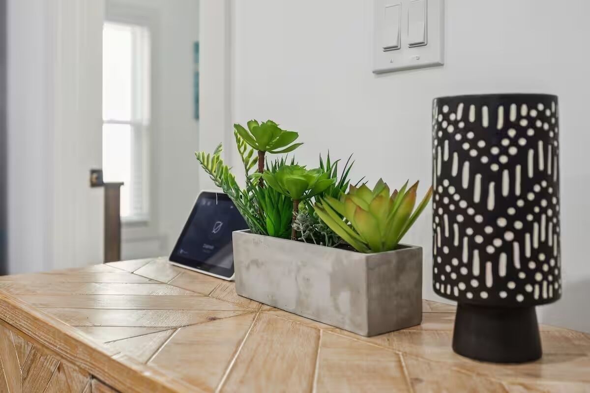 A wooden table with a potted plant, a laptop, and a decorative lamp.