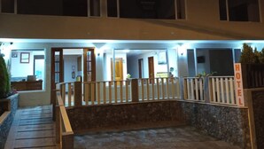 A hotel entrance with a covered walkway, a reception desk, and a sign indicating the hotel's name.