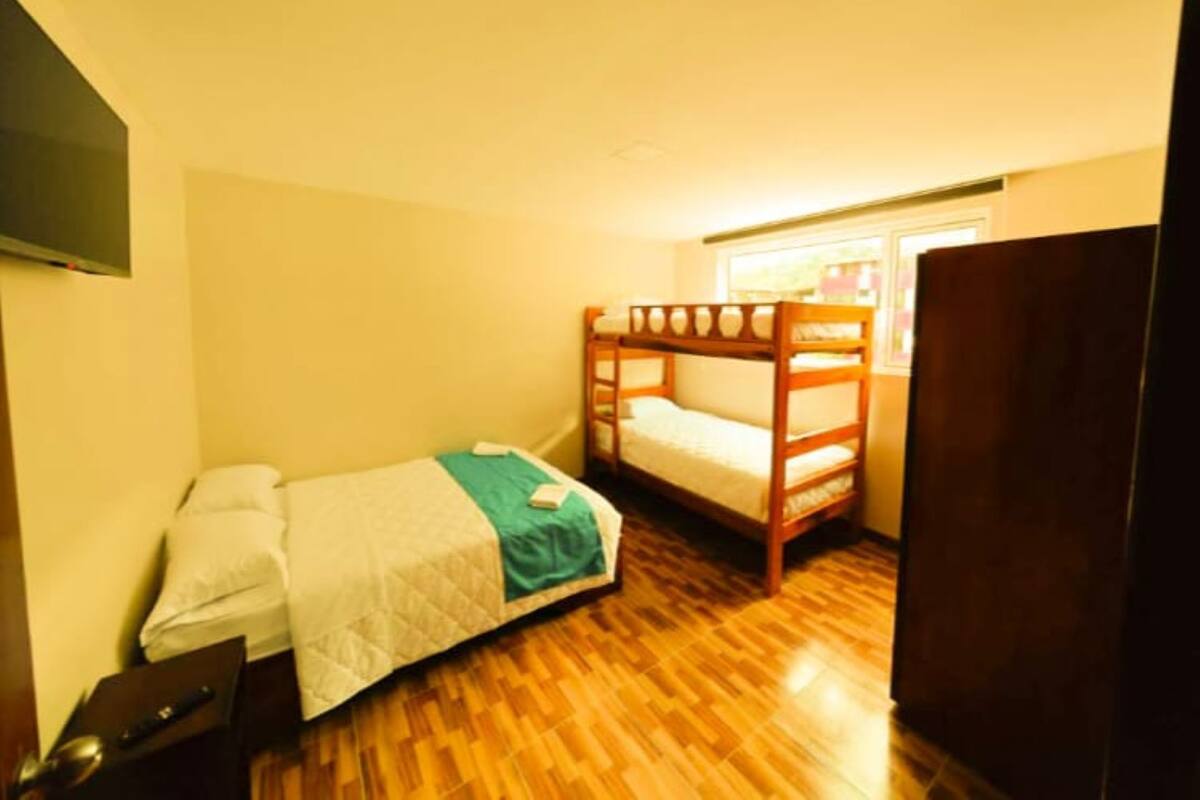 A small, single-room bedroom with a bunk bed, a desk, and a wardrobe.