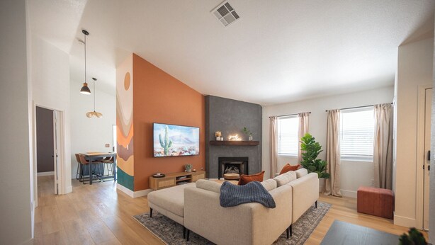Una sala de estar moderna con sofá, televisor, chimenea y comedor con sillas.