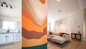 Un apartamento moderno con cocina, sala de estar y un amplio mural abstracto.