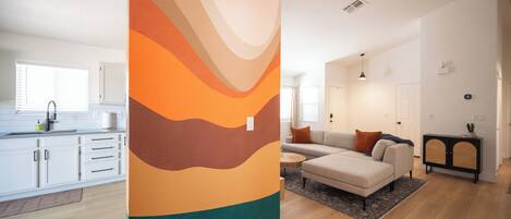 Un apartamento moderno con cocina, sala de estar y un amplio mural abstracto.
