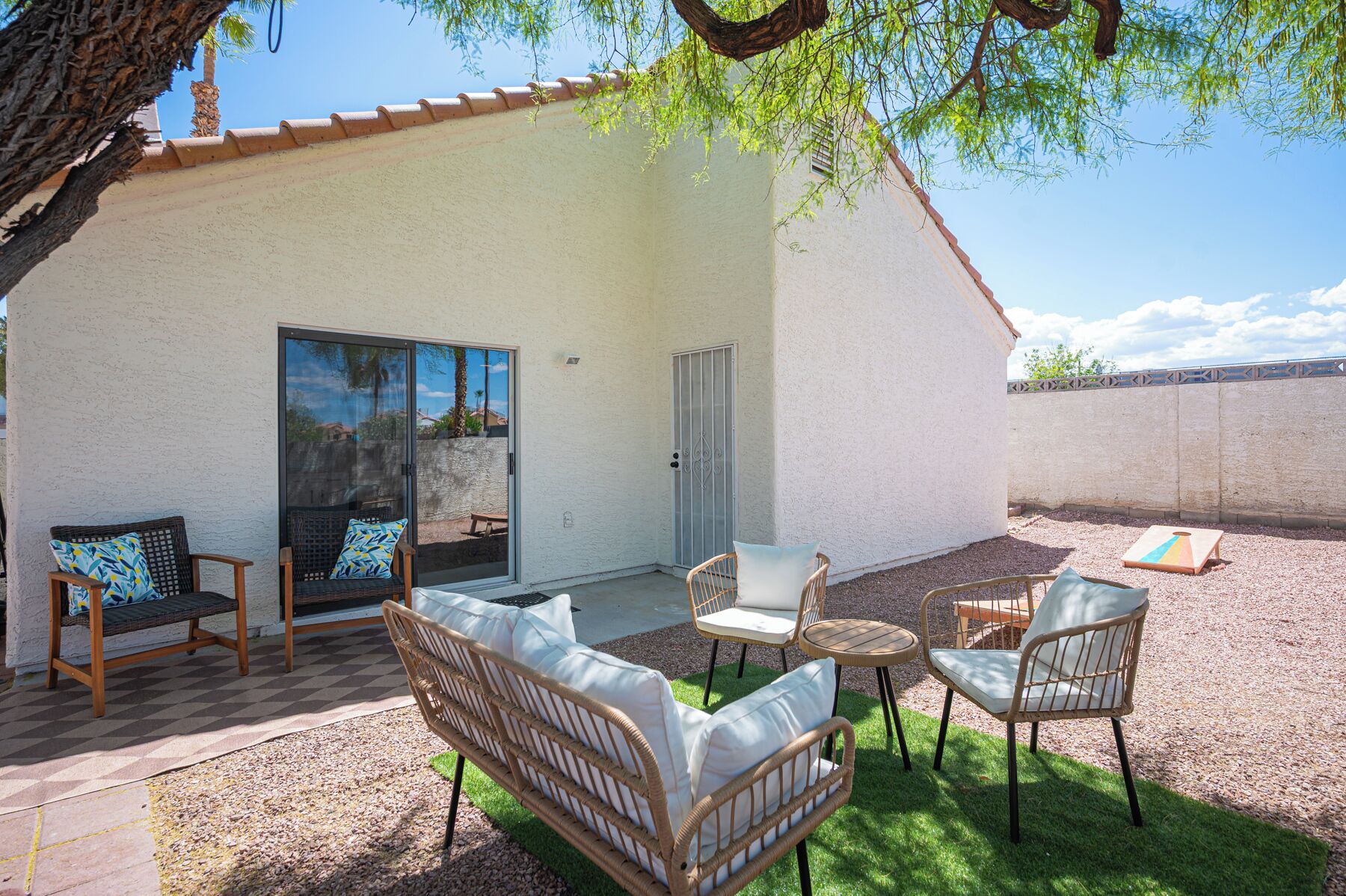 A covered patio area with wicker furniture, a sliding glass door, and a small table.