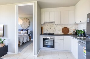 A modern kitchen with white cabinets, a built-in oven, and a stove. - Fremantle Beach Pad - ocean front, cafes, bars (South Fremantle)