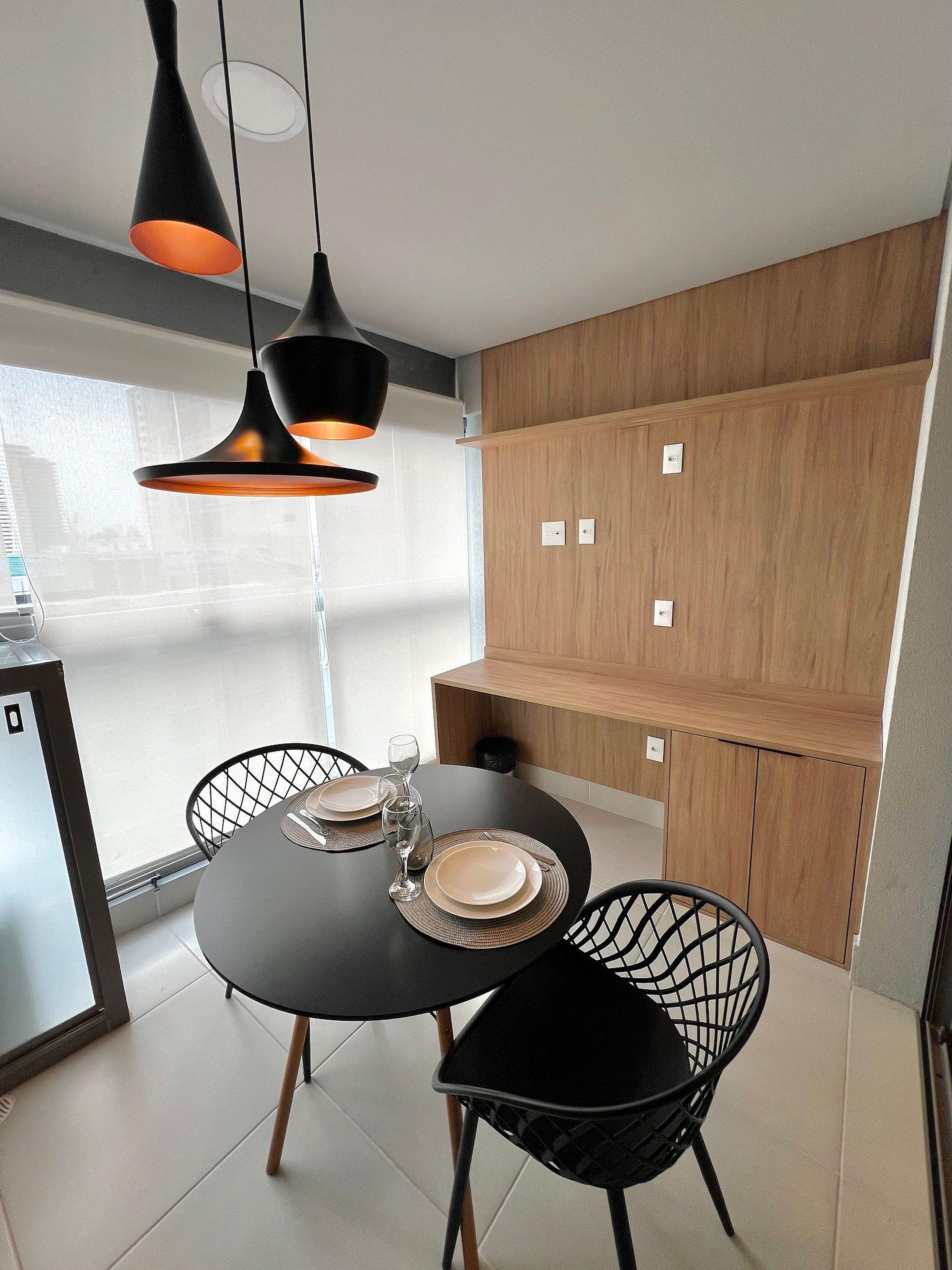 A modern dining area with a round table, black chairs, and pendant lighting.