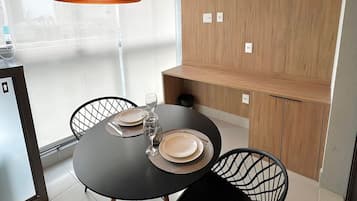 A modern dining area with a round table, black chairs, and pendant lighting.