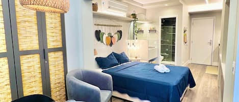 Habitación de hotel moderna con cama, zona de estar con mesa y un gran ventanal con vistas.