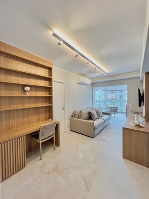 A modern living room with a wooden shelving unit, a sofa, a dining area, and a kitchen counter. - Innvista - AirBrooklin (São Paulo)