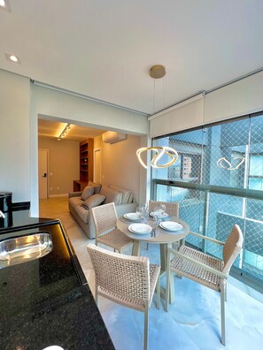 A modern dining area with a round table, wicker chairs, and a glass partition. - Innvista - AirBrooklin (São Paulo)