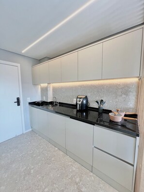 A modern kitchen with a black countertop, stainless steel appliances, and a light-colored backsplash. - Innvista - AirBrooklin (São Paulo)