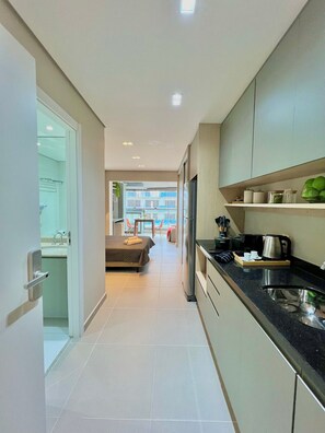 Una cocina moderna con refrigerador, estufa y cafetera. Se ve un comedor con mesa y sillas al fondo.