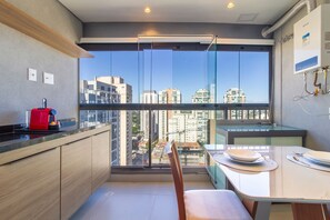 A modern kitchen with a large window, a red coffee machine, and a dining area with a table and chairs. - Innvista - AirBrooklin (São Paulo)