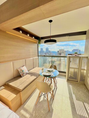 A modern living space with a sofa, dining table, chairs, and a city view. - Innvista - AirBrooklin (São Paulo)
