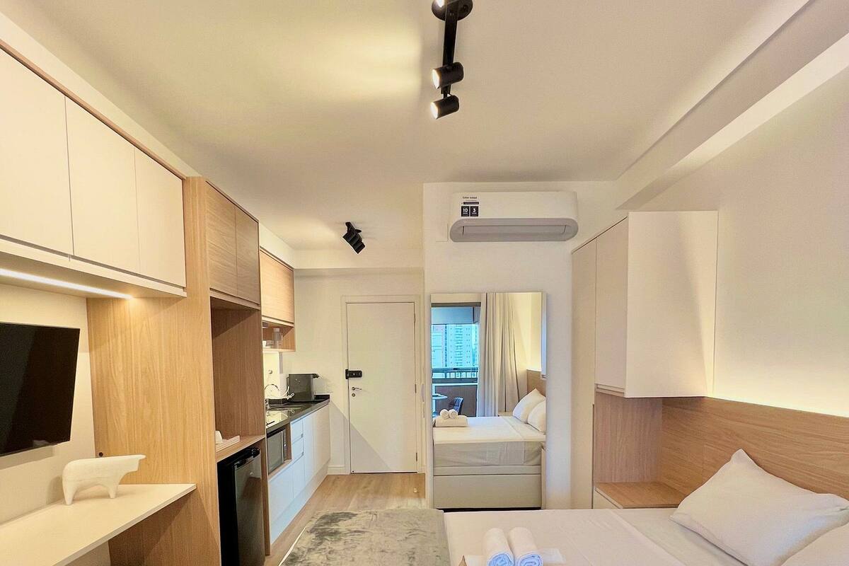Hotellihuoneessa on sänky, penkki, työpöytä, televisio, keittotila ja ilmastointilaite.