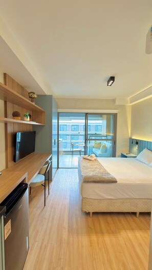 Una habitación de hotel moderna con cama, televisor, escritorio y balcón con vistas.