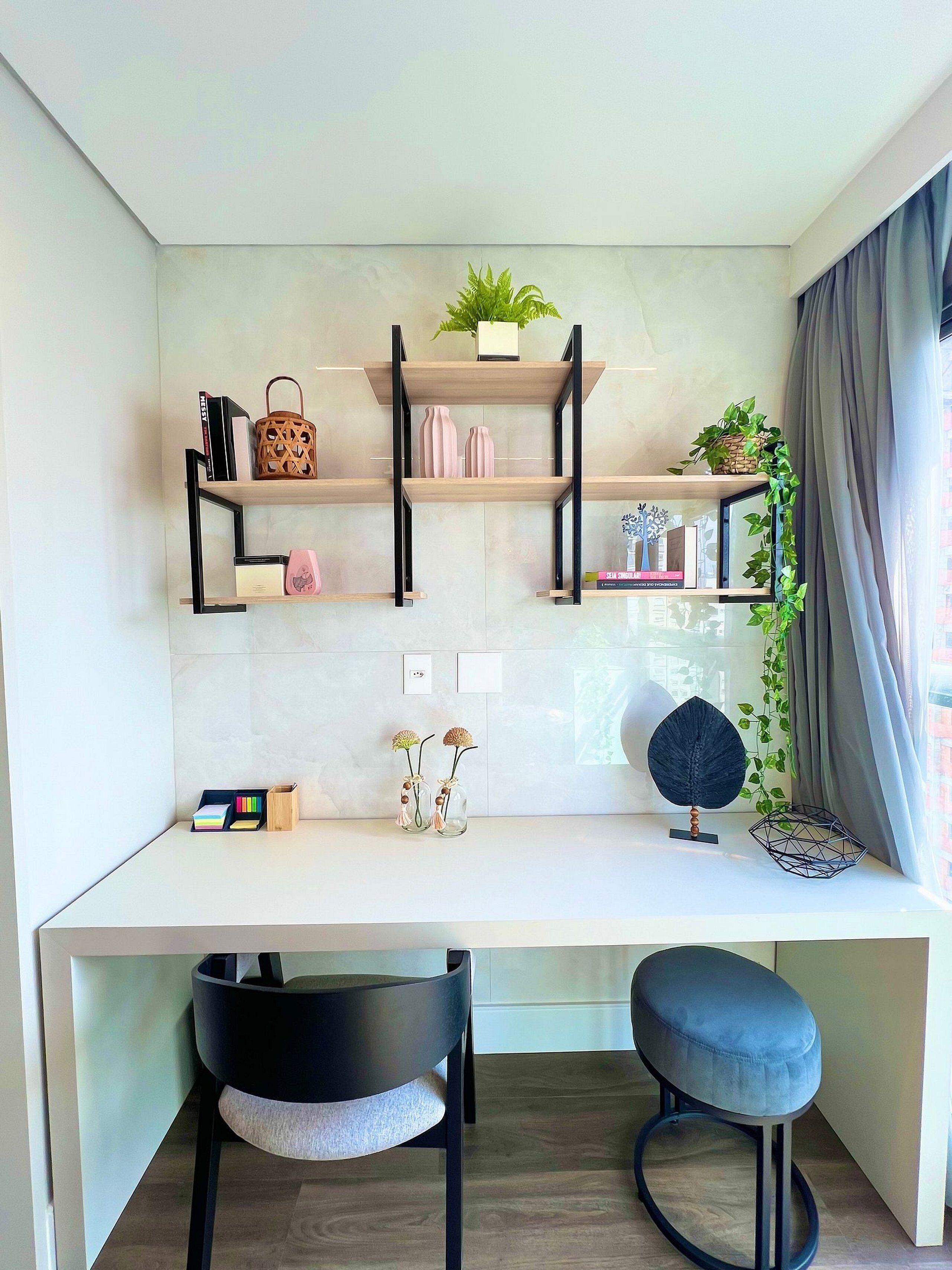 A modern kitchen with a white countertop, black metal shelves, and a small dining area with two stools.
