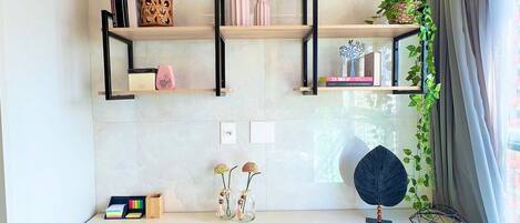 A modern kitchen with a white countertop, black metal shelves, and a small dining area with two stools.
