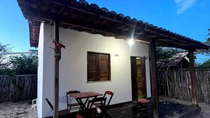 Una casita con techo de tejas, un porche de madera y una sola ventana.