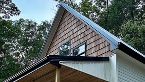 Une maison à deux étages dotée d’une terrasse en bois et d’un porche abrité.