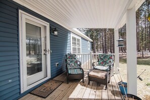 A porch with two chairs, a door, and a window. - Pond Creek Cottage, Tucked Away, Near Boyne Mount! (Boyne Falls)