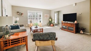 Un salón con sofá, mesa de centro, mueble para televisión y plantas en macetas.