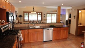 A spacious kitchen with wooden cabinets, a stainless steel dishwasher, and a large island with a sink.