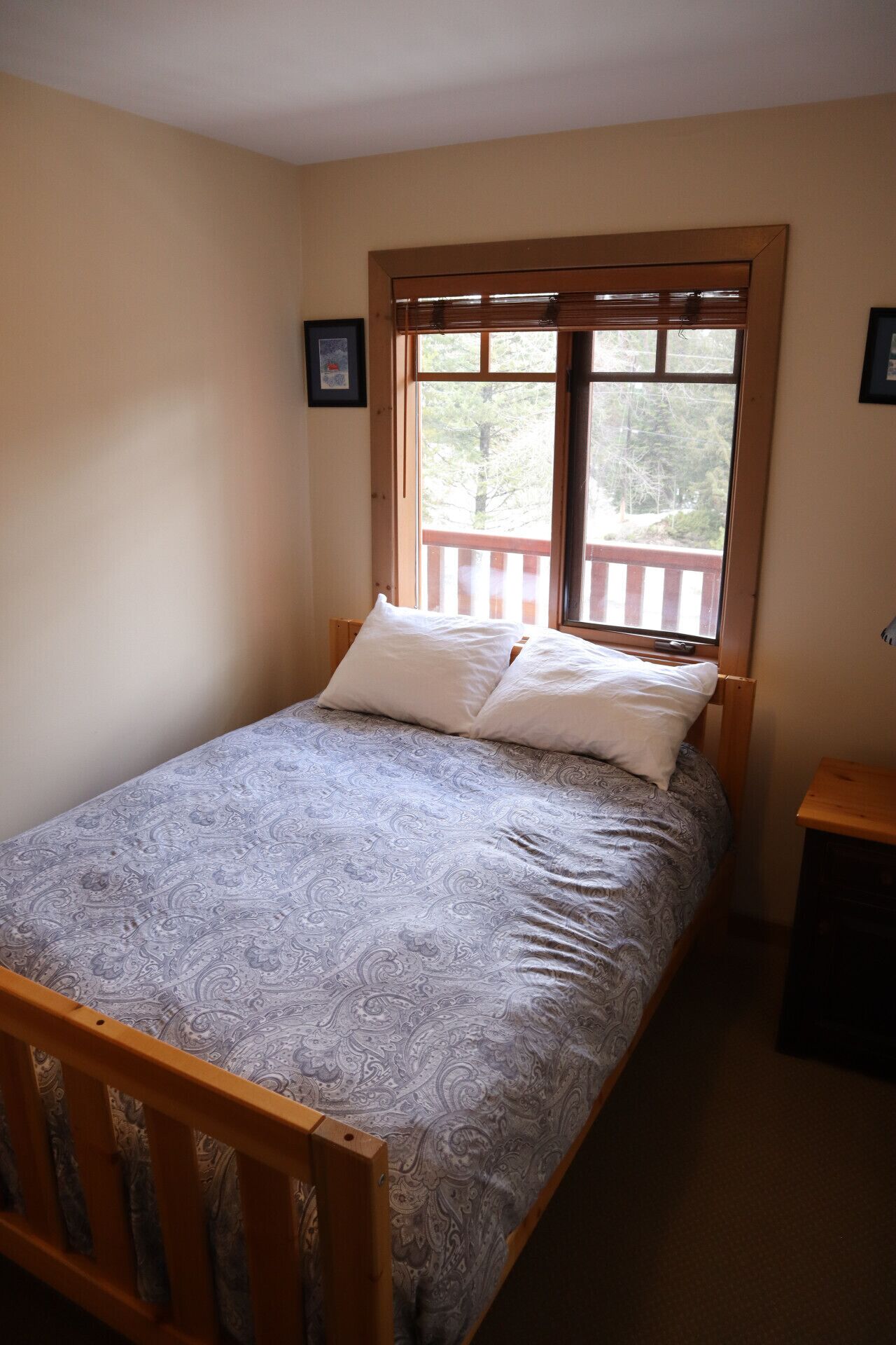 Una camera piccola con un letto singolo, una finestra vista alberi e una testiera in legno.