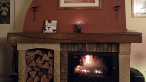 Une cheminée avec un manteau de cheminée, un tableau encadré et un livre intitulé « Le plaisir de déguster le vin ».
