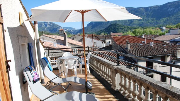 Un balcon doté de chaises longues et d’une table, offrant une vue sur un paysage montagneux.