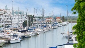 Een jachthaven met veel boten afgemeerd langs de waterkant, omringd door gebouwen met balkons en een heldere lucht.