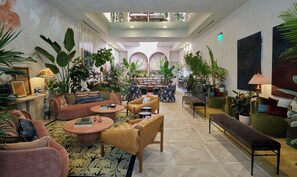 A spacious lobby with a high ceiling, multiple seating areas, and abundant indoor plants. - Charming 2-bedroom Suite in Granger Hotel with Hot Breakfast Buffet (San Diego)