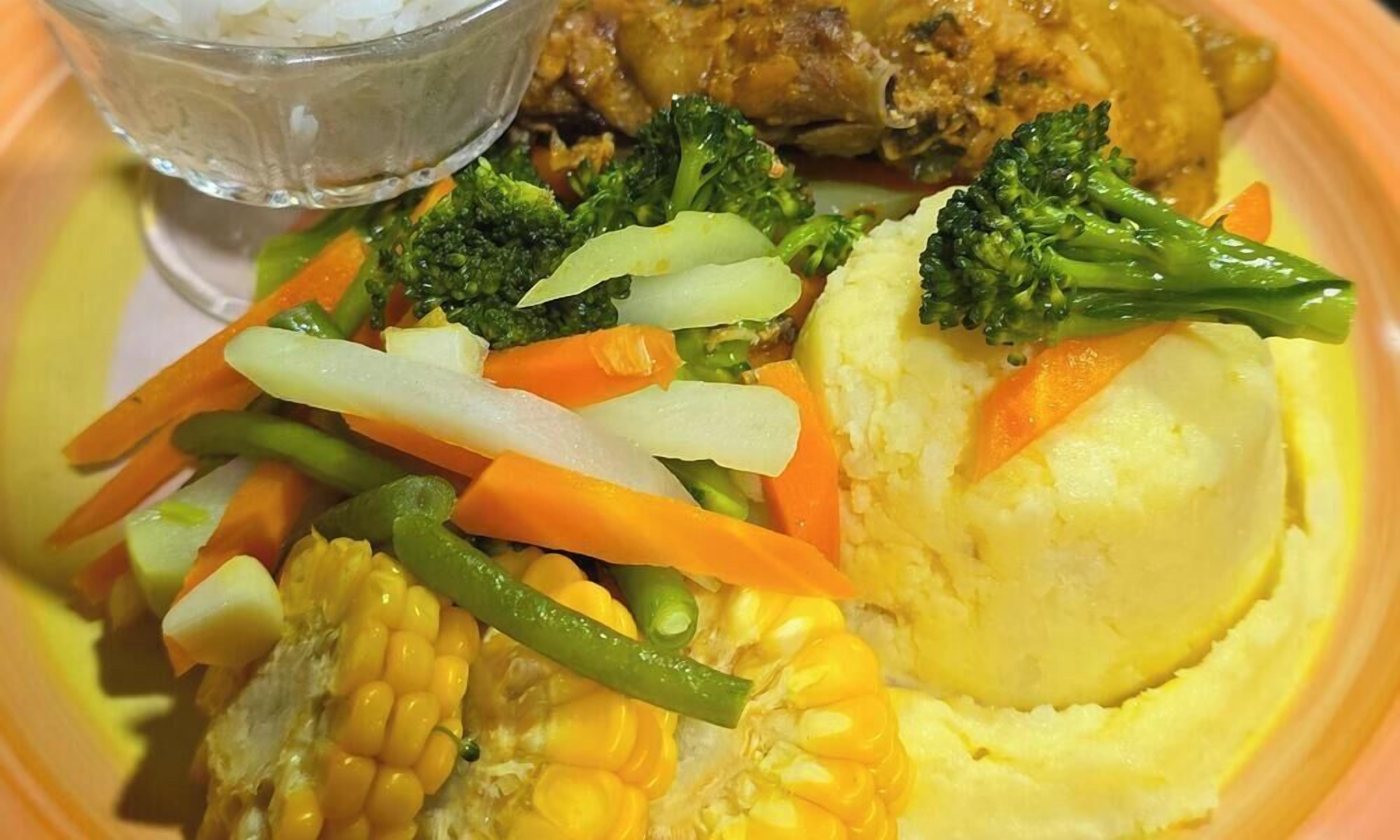 A meal with vegetables, mashed potatoes, and a piece of meat.