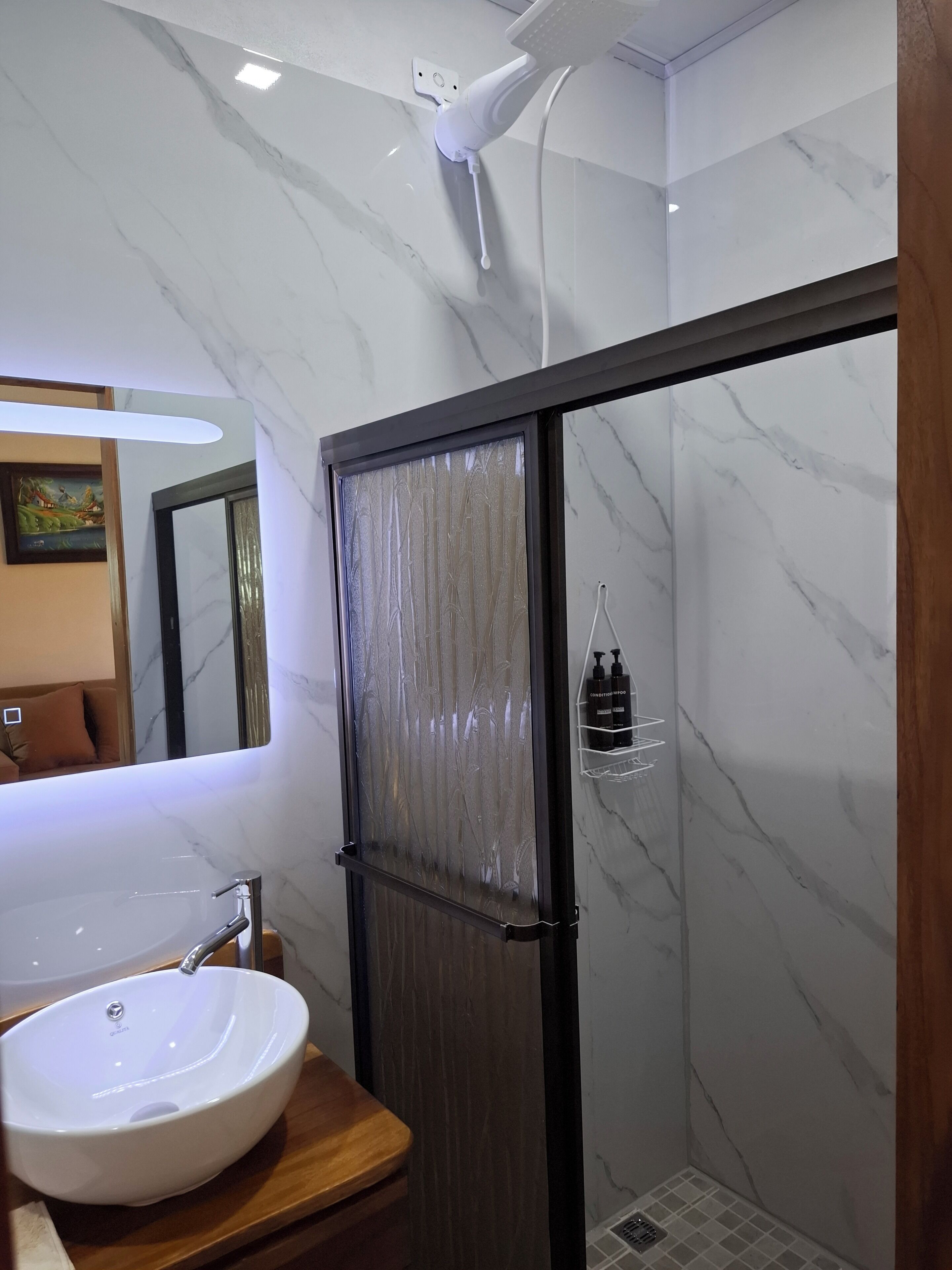Une salle de bain moderne avec un lavabo en marbre, une cabine de douche en verre et un meuble-lavabo en bois.