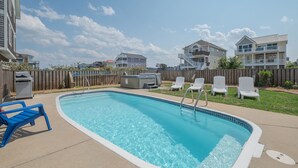 Une piscine avec une terrasse en bois, des chaises longues et un jacuzzi.