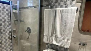 A bathroom with a glass shower enclosure, a toilet, and a sink.