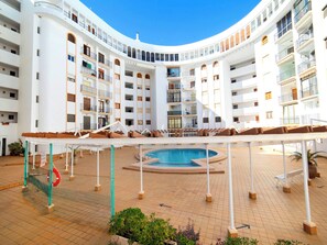 A multi-level hotel with a central pool area, balconies, and a curved architectural design.