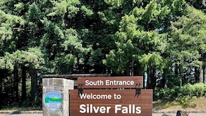 A welcome sign for Silver Falls State Park with a stone base and a wooden signboard.