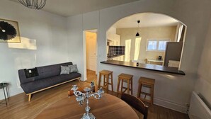 Ein modernes Wohnzimmer mit einem dunkelgrauen Sofa, einem Holzesstisch und einer Chandelier.
