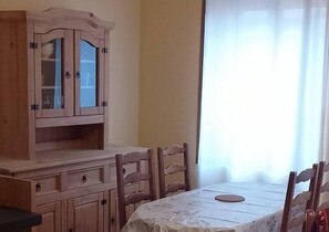 Enjoy meals in this dining area with a table for four, a cabinet, and a window with sheer curtains.