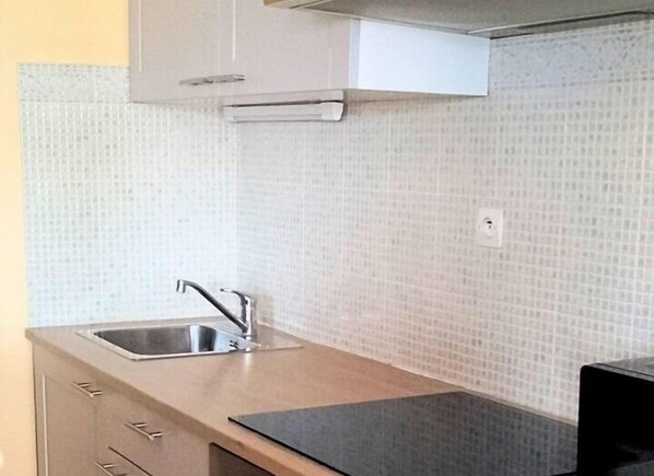 La Concierge Lensoise kitchen features a stainless steel sink, oven, and light and dark wood cabinetry.