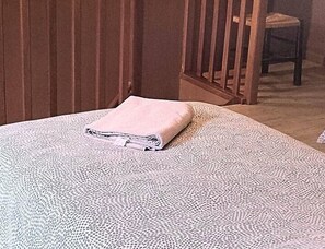 Relax in comfort with a neatly made bed and a plush bedspread, featuring a wooden headboard and chair.