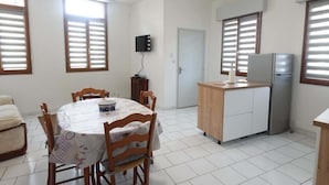 A compact kitchen with a dining table, chairs, a refrigerator, and a TV on the wall. - Le Carvinois, wifi, Carvin centre, 2pers (Carvin)