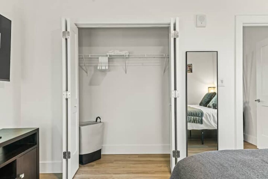 A bedroom with a bed, a wardrobe, and a mirror.