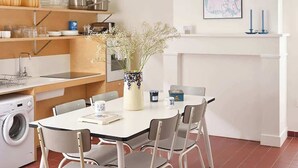 Une cuisine moderne avec un coin repas, un lave-linge et un vase rempli de fleurs sur la table.