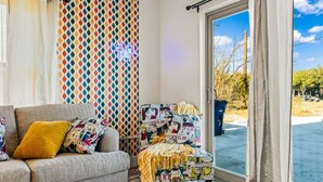 Un salon chaleureux avec un canapé, des coussins à motifs et un mur aux couleurs vives.
