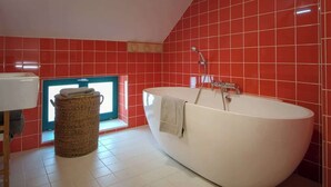 Une salle de bain moderne avec une baignoire sur pieds, un panier en osier et une fenêtre donnant sur un beau paysage.