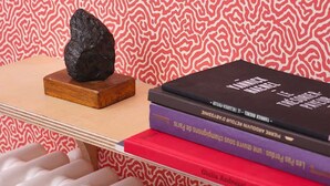 Une pile de livres sur une étagère, avec un papier peint à motifs en arrière-plan.